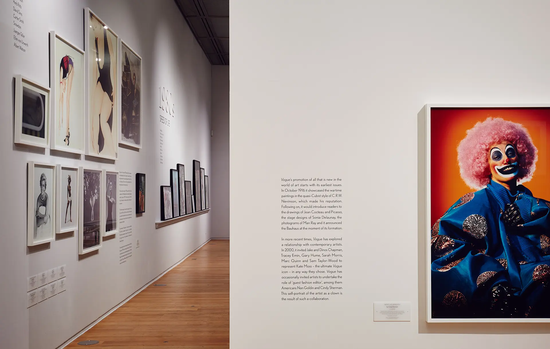 An exhibition shot with justified type on a white wall and a clown portrait.